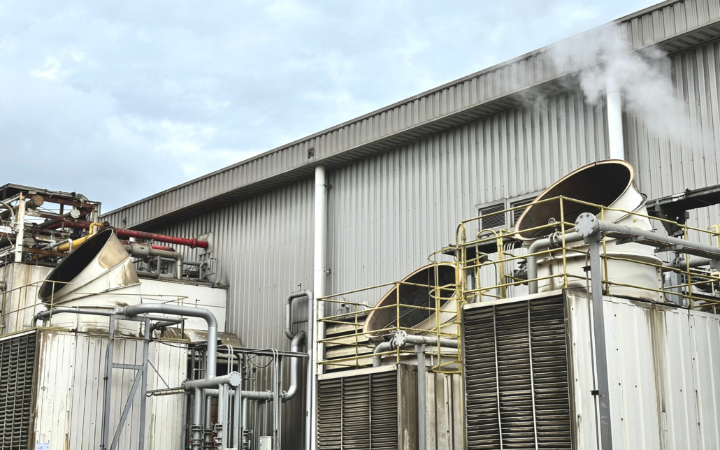 Industrial cooling tower system emitting vapor under blue sky