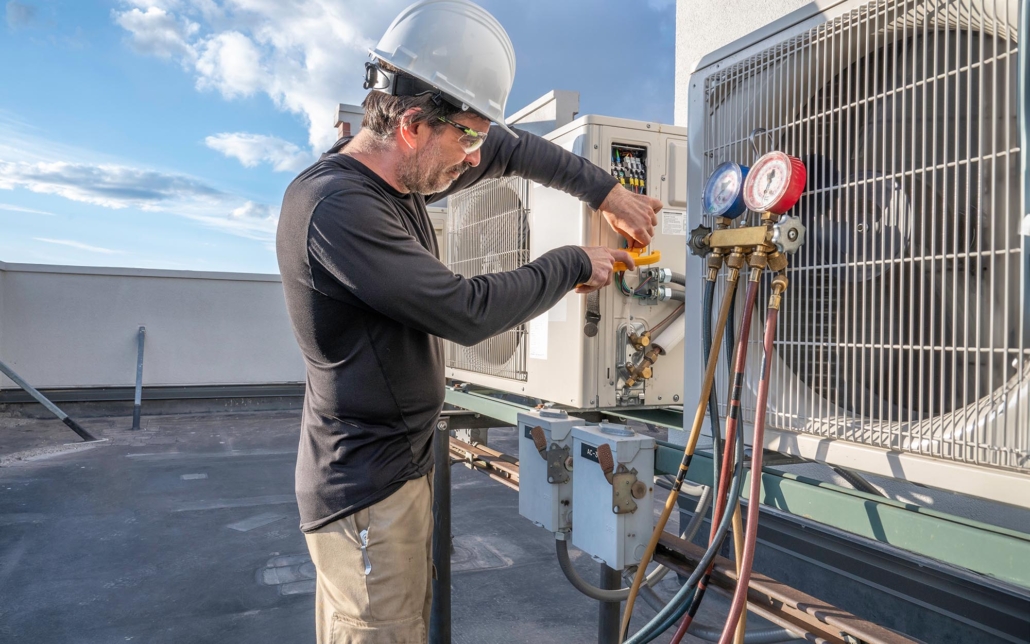 Side view of a man working on an air conditioning unit