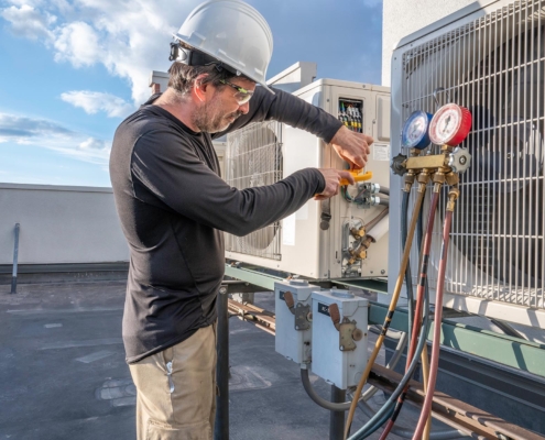 Side view of a man working on an air conditioning unit