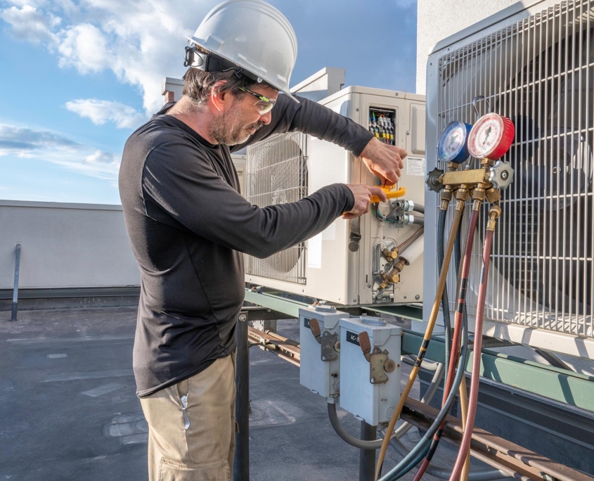 Side view of a man working on an air conditioning unit