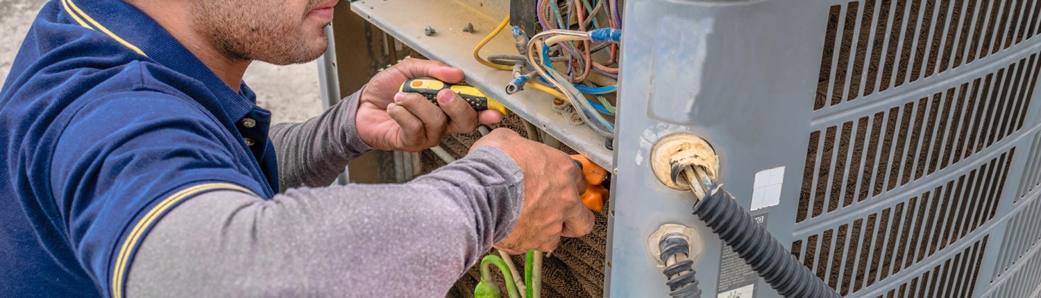 Side view of a man doing maintenance on an HVAC unit