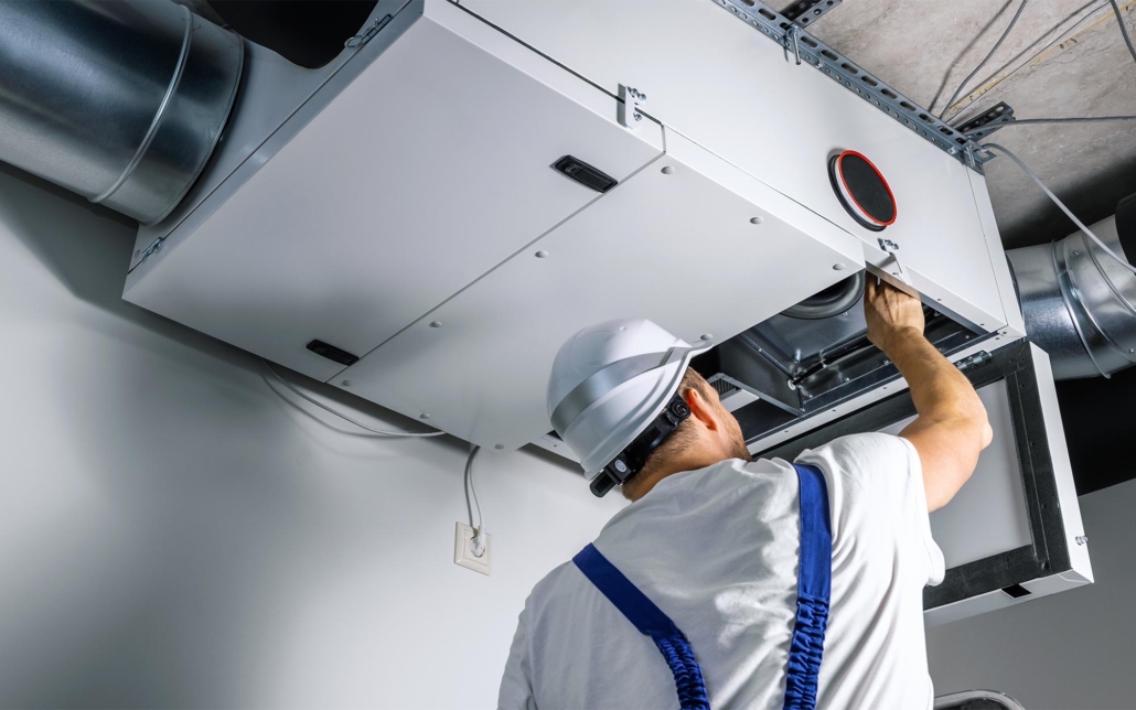 Worker cleaning air ducts and filters in commercial building