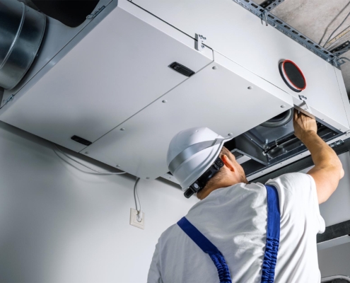 Worker cleaning air ducts and filters in commercial building
